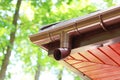 Roof of house with plastic rain gutter on beautiful natural background with green vegetation Royalty Free Stock Photo