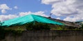 Roof house temporary repair on badly storm damaged roof with a big leaky hole in shingles and rooftop covered hole with green Royalty Free Stock Photo