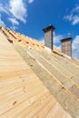 Roof insulation. New wooden house under construction with chimneys against blue sky. Royalty Free Stock Photo