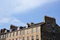 The roof of an old house with rows of windows and brick walls. On the roof are rows of chimneys for heating Royalty Free Stock Photo