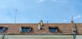 The roof of the old house. Tiles, small wooden viewing windows, stone chimneys