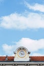 Roof of an old train station with a beautiful clock and a summer sky