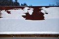 Roof with rain gutter in winter. Roof with asphalt shingles covered with snow and icicles Royalty Free Stock Photo