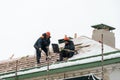 Roof repairs in winter. Two workers repair the roof on a frosty and snowy day. Men with shovels remove snow from the roof Royalty Free Stock Photo