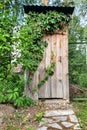 Wooden outdoor toilet overgrown with ivy. Royalty Free Stock Photo