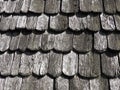 Roof shingles as a traditional rural roof covering. Tiled acute angled cross slab roofing piece material close-up
