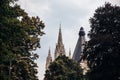 Roof and spire of buildings Gothic monuments, Baroque architecture in background, trees, Rowan green crowns foreground