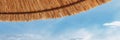 The roof of a straw umbrella against the background of blue water Royalty Free Stock Photo