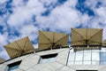 roof terrace restaurant at top of glass curtain wall facade. beige square parasols. green plants