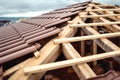 Roof under construction with stacks of brown, modern tiles covering house