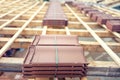 Roof under construction with stacks of brown roof tiles prepared on wooden structure