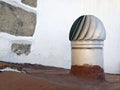 Roof ventilator with typical Canarian white stone wall background. Turbine ventilator installed on painted roof. Rotating vent cap