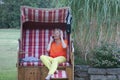 A roofed wicker beach chair, the attractive woman with a bathing suit and a mobile phone, here time stands still