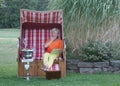 With the tablet in her hand, the young woman in a roofed wicker beach chair reads the e-mails for her birthday