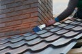 Roofer builder worker attach metal sheet to the chimney. Unfinished roof construction