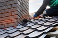 Roofer builder worker attach metal sheet to the chimney. Unfinished roof construction.