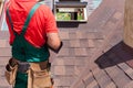 Roofer builder worker with bag of tools installing roofing shingles.