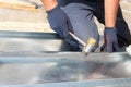 Roofer builder worker finishing folding a metal sheet using rubber mallet. Royalty Free Stock Photo