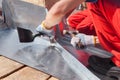 Roofer builder worker finishing folding a metal sheet using rubber mallet. Royalty Free Stock Photo