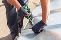 Roofer builder worker finishing folding a metal sheet using special pliers with a large flat grip. Royalty Free Stock Photo