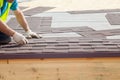 Roofer builder worker installing Asphalt Shingles or Bitumen Tiles on a new house under construction