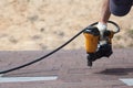 Roofer builder worker with nailgun installing Asphalt Shingles or Bitumen Tiles on a new house under construction. Royalty Free Stock Photo