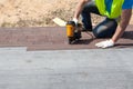 Roofer builder worker with nailgun installing Asphalt Shingles or Bitumen Tiles on a new house under construction. Royalty Free Stock Photo