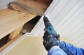 Roofer contractor install soffit boards on rooftop with screw gun