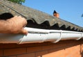 Roofer contractor installing and repair rain gutter pipeline. Guttering repair with contractor hands Royalty Free Stock Photo