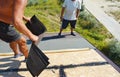 Roofer contractors installing asphalt shingles on house construction roof top. Roofing