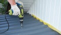 Roofer with crew gun installing  lightweight metal roof tiles roofing  construction Royalty Free Stock Photo