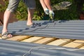 Roofer with crew gun installing metal roof sheets. Roofing construction Royalty Free Stock Photo