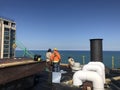 Roofer and crew working on a smooth modified flat roof, safety compliant roofing project in progress