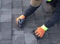 Roofer cuts a shingle to fit during repair work.