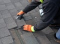 Roofer cuts a shingle to fit during repair work.