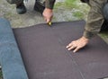 Roofer cutting roll roofing felt or bitumen during waterproofing works