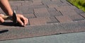 Roofer hands installing asphalt shingles on house construction roof corner with hammer and nails. Roofing Construction Panorama