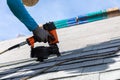 Roofer installing roof shingles with nail gun