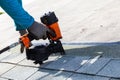 Roofer installing roof shingles with nail gun