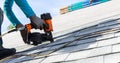 Roofer installing roof shingles with nail gun