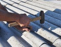 Roofer repair asbestos roof sheet with nails and hammer. Nailing asbestos cement sheet repair