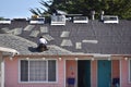 Roofer replacing the roof tiles at a pink colored motel