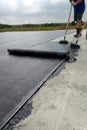 Roofer worker painting bitumen praimer at concrete surface by the roller brush Waterproofing Royalty Free Stock Photo