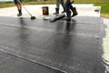 Roofer worker painting bitumen praimer at concrete surface by the roller brush Waterproofing Royalty Free Stock Photo