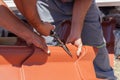 Roofers cut a metal tile using cutting pliers. Royalty Free Stock Photo