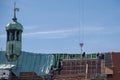 Roofers working on roof framework of old church with copper tower on sunny day