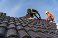 2 roofers working on the working at height to install the Concrete Roof Tiles on the new roof of new modern building construction Royalty Free Stock Photo