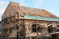 Roofing construction. Brick house with wood scaffolding and unfinished roofing construction