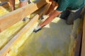 Roofing construction: building contractors in protective gloves are installing glass wool sheets, batts on the rooftop below