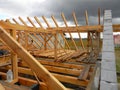 Roofing construction: a close up on an unfinished roof framing with wooden ceiling joists, roof beams, underpurlins, rafters, and